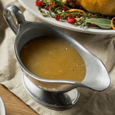 there is a gravy in a silver gravy pot on the table