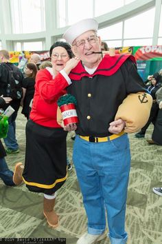 an older man and woman dressed up in costumes at a convention or show, one is talking on the phone