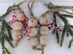 three wooden snowman ornaments hanging from twine