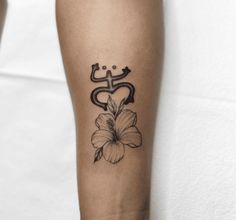 a black and white photo of a flower tattoo on the left arm, with an omen symbol behind it