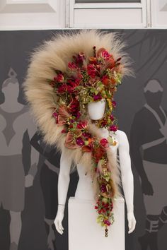 a white mannequin with flowers on it's head and fur around its neck