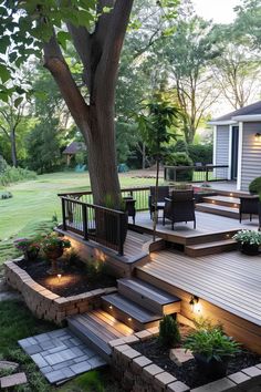 an outdoor deck with steps and lighting in the middle of it, next to a tree