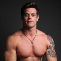 a shirtless man with tattoos on his arm and chest posing for a photo in front of a black background