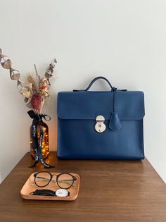 "One and only!  High quality handmade briefcase comes with navy blue colour. Everything is made by hand with great craftsmanship. This simple and minimal design will be good match with business man and woman. Outside of leather is premium italian leather that is very smooth and sleek. And inner lining is dark brown leather which has unique texture. This briefcase has one big pocket that you can put up to 13 inches laptop and two small pockets that you can put notebook or phone, passport and etc. Also I have used high quality japanese lock that gives you more tidy and simple look. Size detail : 13.7\" X 10\" X 2.8\" (35cm X 27cm X 7cm) * Merchandise on display may have some scratches on the surface. This cannot be the reason for refund or return." Luxury Blue Briefcase For Office, Blue Top Handle Satchel For Business, Classic Navy Bag For Formal Occasions, Formal Blue Smooth Grain Bag, Classic Navy Formal Bag, Formal Blue Bag With Leather Lining, Modern Navy Bags For Formal Occasions, Timeless Blue Business Bag, Timeless Blue Business Bags