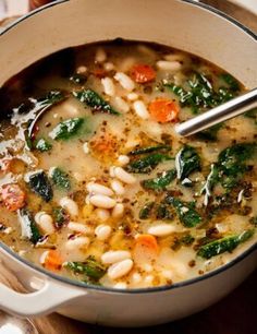 a pot filled with soup and vegetables on top of a wooden table