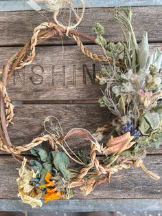 a wreath with dried flowers on top of a wooden table next to a sign that says gin