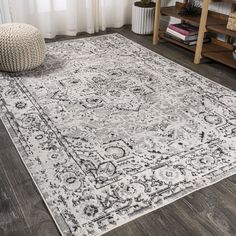 a white and black rug with an ornate design on the floor in front of a window