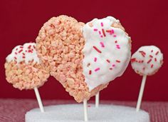 three heart shaped cake pops with white frosting and sprinkles on top