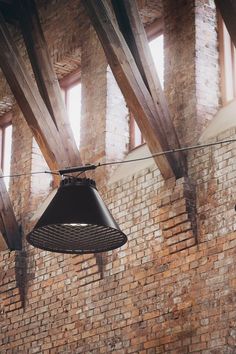 a bell hanging from the side of a brick wall in an old building with exposed beams