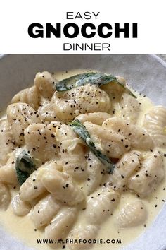 a white bowl filled with pasta covered in sauce and topped with basil leaves on top