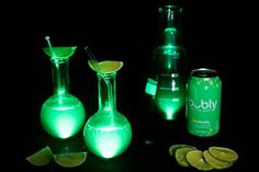 three different types of alcoholic beverages lit up in the dark with limes and lemon wedges