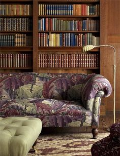 a couch and ottoman in front of a bookcase with books on the shelves behind it