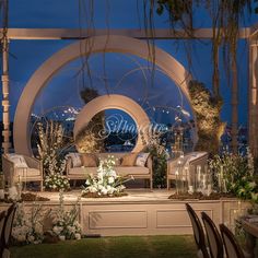 an outdoor seating area with flowers and greenery on the lawn, surrounded by large circular archways