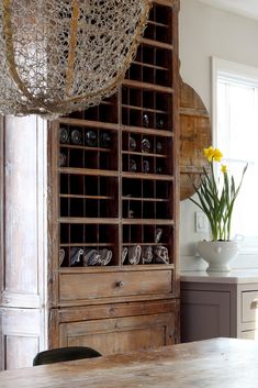 a wooden cabinet filled with lots of shoes next to a vase full of yellow flowers