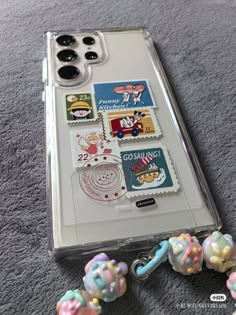 a phone case with some stamps and beads on the ground next to it's holder