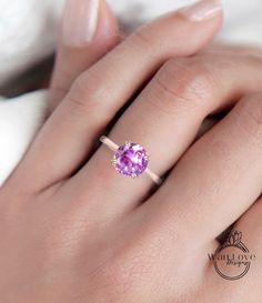 a woman's hand with a ring on her finger and a pink stone in the middle