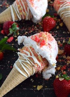 three ice cream cones with strawberries on the side