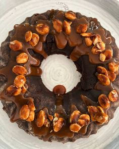 a chocolate cake covered in nuts and drizzled with icing on a plate