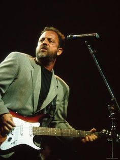 a man with a guitar in front of a microphone and an instrument on the stage