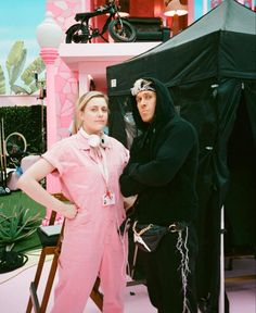 two women standing next to each other in front of a black and white tent with pink walls