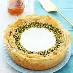 a cake on a plate next to a coffee cup and spoon with nuts in it