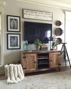 a living room with a television and pictures on the wall above it, along with a rug