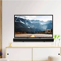 a flat screen tv mounted on the wall above a white cabinet in a living room