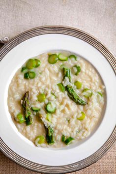 a white bowl filled with rice and asparagus on top of a wooden table