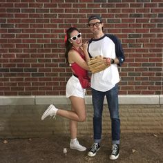 a man standing next to a woman in front of a brick wall holding a catchers mitt