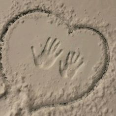 two hands in the shape of a heart drawn on snow