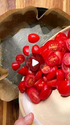 someone is cutting up tomatoes on a wooden table