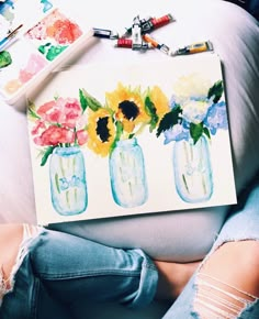 a woman laying on top of a white couch next to a vase filled with sunflowers