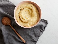 a bowl of mashed potatoes on top of a gray napkin with a wooden spoon