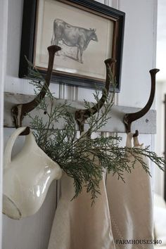 two towels hanging from hooks in front of a cow print on the wall behind them