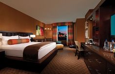 a hotel room with a large bed, desk and television in front of a window