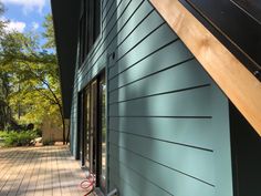 the side of a house with wood flooring and blue paint on it's exterior