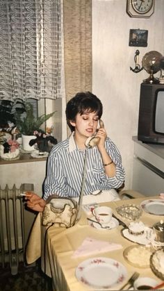 a woman sitting at a table talking on the phone