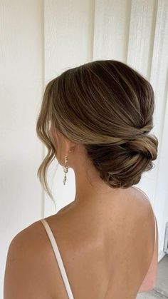 a woman with her back to the camera, wearing a white dress and gold earrings