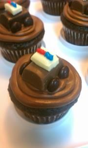 chocolate cupcakes with frosting and decorations on them sitting on a white surface