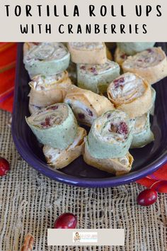 tortilla roll ups with cranberry filling on a blue plate next to cherries