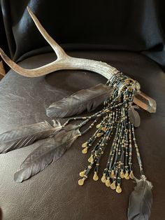 an antler with beads and feathers on it's back rests on a leather seat