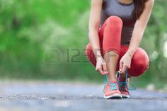 a woman squatting down on the ground with her feet crossed and wearing running shoes