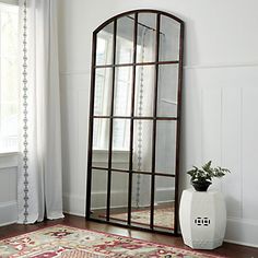 a large mirror sitting on top of a wooden floor next to a vase filled with flowers