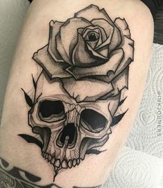 a skull and rose tattoo on the thigh