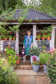 a woman standing in front of a garden shed