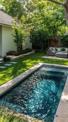 a pool in the middle of a yard with green grass and lawn furniture next to it