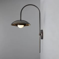 a lamp that is on the wall next to a light fixture in a room with gray walls