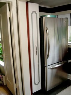 a stainless steel refrigerator in a kitchen with black and white stripes on the wall behind it