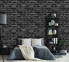 a bedroom with black brick walls and grey bedding