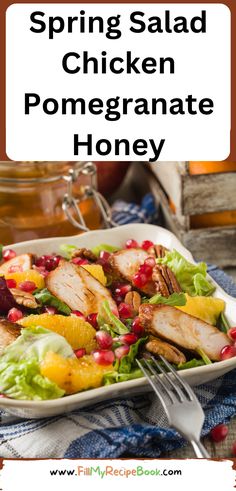 a white plate topped with chicken and pomegranate salad next to a jar of honey